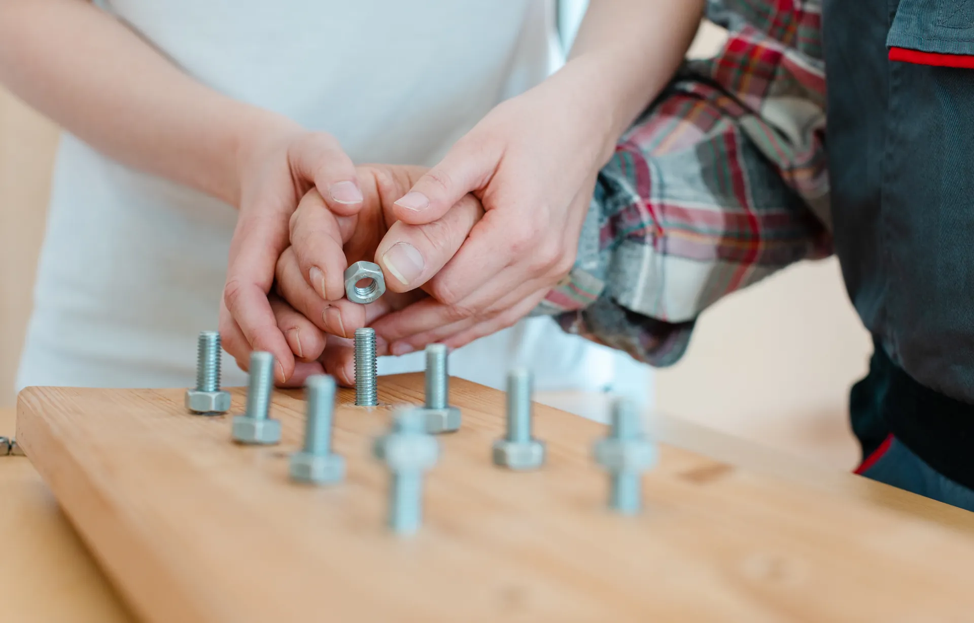 Hände setzen eine Mutter auf einen Bolzen eines Therapiegeräts